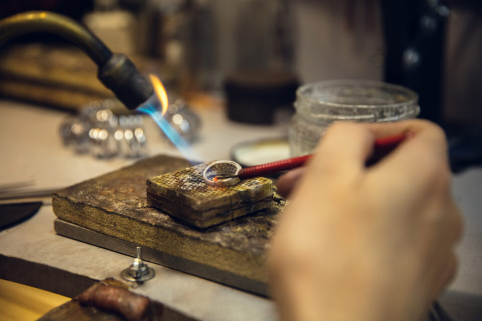 close-up-hands-jeweller-goldsmiths-making-golden-ring-with-gemstone-using-professional-tools